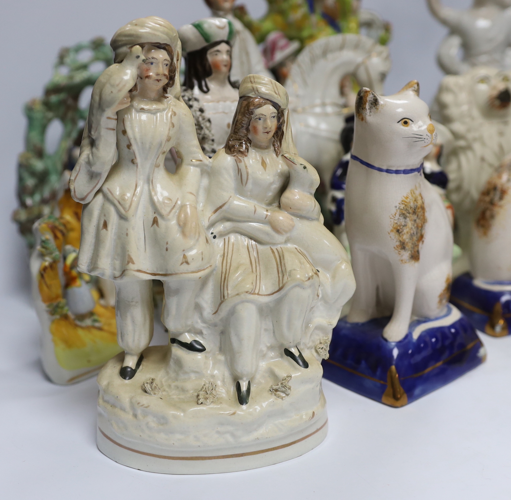 Seven Staffordshire flat backs, including a gentleman on horse back, two seated lovers, a similar pair of King Charles Spaniels, and a pair of Staffordshire style cats, tallest 32cm